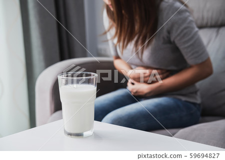 Woman having bad stomach ache with a glass of 59694827