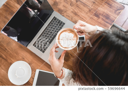 Young woman drinking coffee cup using laptop computer. 59696644