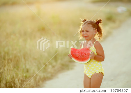 Beautiful little girl eating watermelon outdoors closeup photo Beautiful little girl eating watermelon outdoors closeup photo 59704807