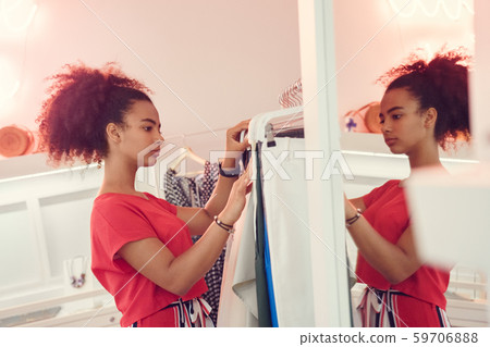 Choosing Clothes. African teenager girl standing choosing clothes from wardrobe looking at variety 59706888
