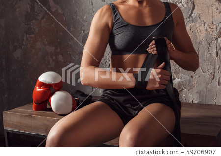Boxing. Woman boxer sitting on bench wrapping bandage around hand concentrated close-up 59706907