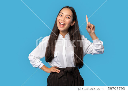 Freestyle. Young woman wearing shirt and skirt standing isolated on blue pointing up at copy space 59707793