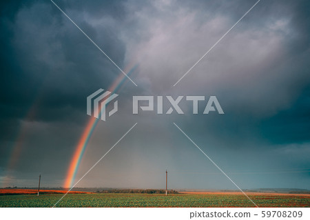 Dramatic Sky During Rain With Rainbow On Horizon Above Rural Landscape Field. Agricultural And Dramatic Sky During Rain With Rainbow On Horizon Above Rural Landscape Field. Agricultural And 59708209