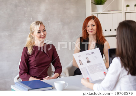 HR and her assistant talk with potential employee and discuss her resume. Selective focus 59708579