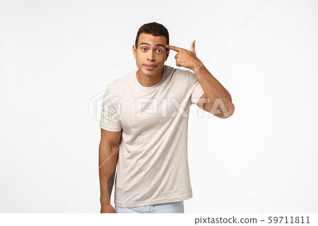 Annoyed arrogant and aggressive handsome brazilian guy rolling finger over temple and stare camera Annoyed arrogant and aggressive handsome brazilian guy rolling finger over temple and stare camera 59711811