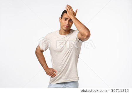 Upset and disappointed gloomy handsome guy in casual t-shirt, punch forehead, facepalm motion, smirk 59711813