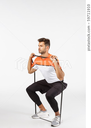 Vertical, full-length shot handsome focused young bearded sportsman in activewear, perform squats 59711910