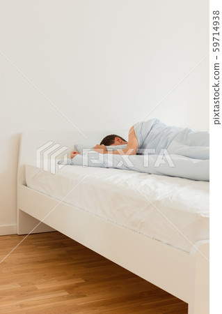 Man sleeping on a white bed 59714938