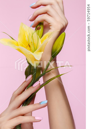 Beautiful pink and blue manicure with crystals on female hand with flowers. Close-up. 59714954