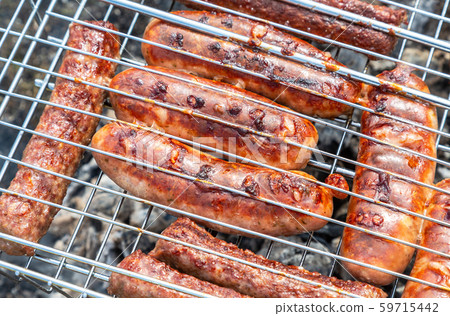 Appetizing sausages from meat on a metal grid 59715442