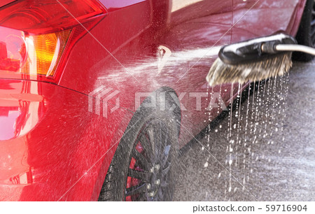 Red car washed in self service carwash, detail on white soap foam spraying from washing brush, drops Red car washed in self service carwash, detail on white soap foam spraying from washing brush, drops 59716904
