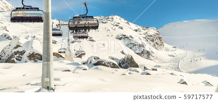 Ski lift ropeway on hilghland alpine mountain winter resort on bright sunny day. Ski chairlift cable Ski lift ropeway on hilghland alpine mountain winter resort on bright sunny day. Ski chairlift cable 59717577