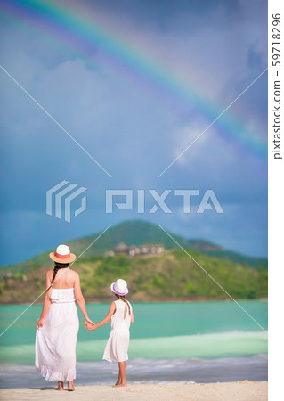 Beautiful mother and daughter on Caribbean beach with amazing rainbow on background 59718296