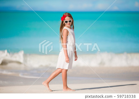 Beautiful little girl in dress at beach having fun. Funny girl enjoy summer vacation. Beautiful little girl in dress at beach having fun. Funny girl enjoy summer vacation. 59718338