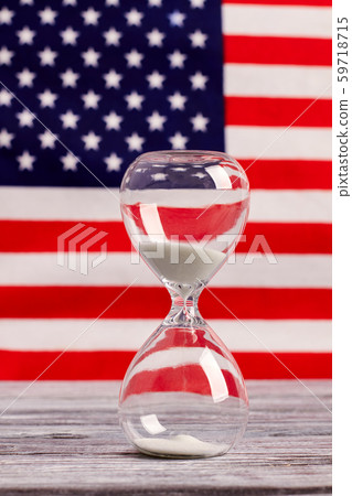 Hourglass on table with USA flag in the background. 59718715