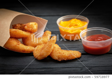 Fried tempura shrimps in paper to-go box. Served with sauces over black background. Copy space. Fast 59718977