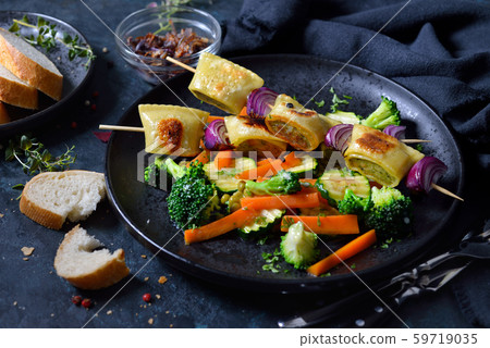 Fried Swabian meat ravioli skewers served with buttered vegetable and roasted onions Fried Swabian meat ravioli skewers served with buttered vegetable and roasted onions 59719035