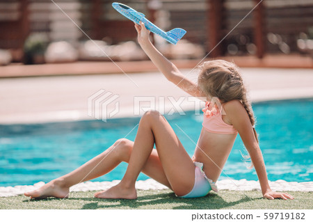Beautiful little girl having fun near an outdoor pool Beautiful little girl having fun near an outdoor pool 59719182
