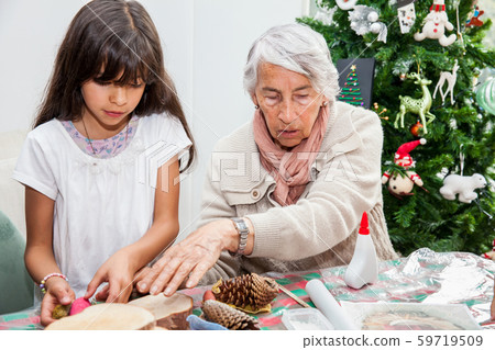 Grandmother teaching her granddaughter how to make christmas Nativity crafts 59719509