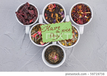 Variety of dried tea in cups on gray background. Variety of dried tea in cups on gray background. 59719738