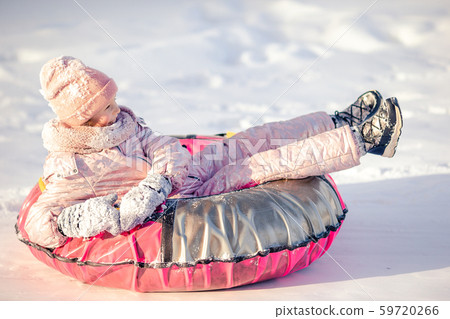 Adorable little happy girl sledding in winter snowy day. Adorable little happy girl sledding in winter snowy day. 59720266