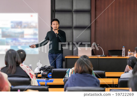 Asian Speaker or lecture with casual suit on the stage presenting via projector screen in the conference hall or seminar meeting room to Audience, business education and Seminar concept 59722269