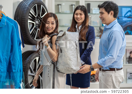 Asian couple holding and using bag in car showroom, 59722305