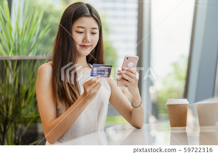 Young Asian woman using credit card with mobile phone for online shopping in coffee shop or coworking space beside window mirror, technology money wallet and online payment concept, credit card mockup Young Asian woman using credit card with mobile phone for online shopping in coffee shop or coworking space beside window mirror, technology money wallet and online payment concept, credit card mockup 59722316