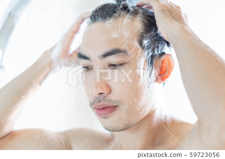 Closeup young man washing hair with with shampoo 59723056