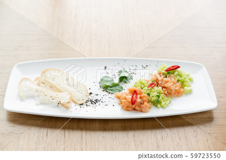 Salmon tartare with cucumber and sesame seeds. Tasting dish on a wooden table. 59723550