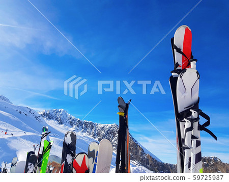 Image of multi-colored skis and snowboards in snow at winter resort in afternoon. Image of multi-colored skis and snowboards in snow at winter resort in afternoon. 59725987