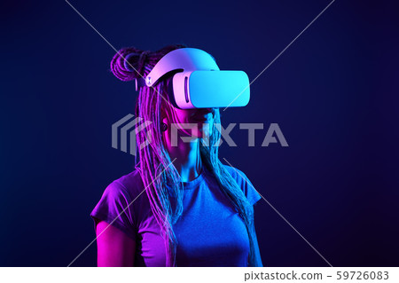 Woman is using virtual reality headset. Neon light studio portrait. 59726083