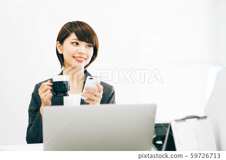 女人在工作休息時看著智能手機喝咖啡 女人在工作休息時看著智能手機喝咖啡 59726713