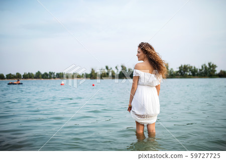 Rear view of young woman at summer festival, standing in lake. 59727725