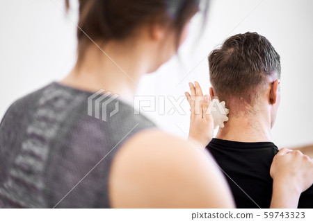 Brunette girl makes massage to young man with white massage ball 59743323