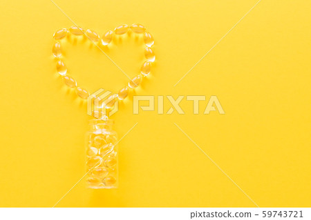 golden omega capsules like heart on yellow background, flat lay golden omega capsules like heart on yellow background, flat lay 59743721
