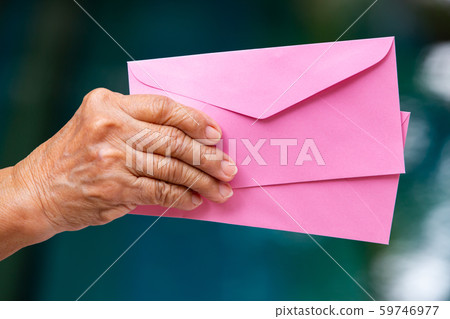 Senior woman's right hand holding 2 pink envelopes in bokeh blue swimming pool background, Close up shot 59746977