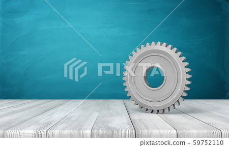 3d rendering of light-grey metal gearwheel standing on wooden floor near blue wall with some copy 59752110