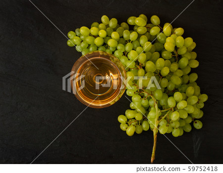 White Wine Glass on Ripe Green Grapes Background 59752418