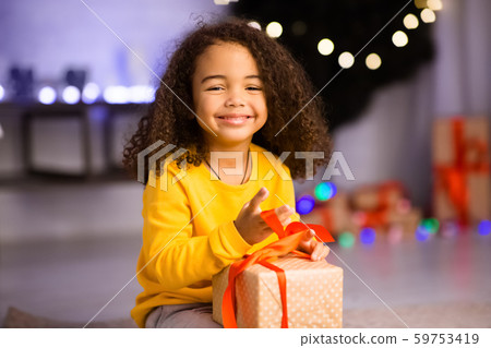 Adorable african american kid enjoying Christmas gift at home 59753419