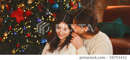 Man in love whispering woman sweet words on Christmas Eve Man in love whispering woman sweet words on Christmas Eve 59753432