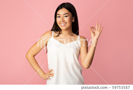All right. Asian girl gesturing OK sign, pink background 59753587