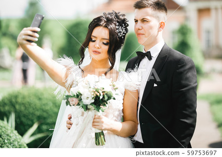Young wedding couple taking a selfie of themselves Young wedding couple taking a selfie of themselves 59753697
