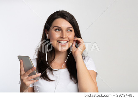 Young Woman In Earphones Listening Music On Cellphone, White Background Young Woman In Earphones Listening Music On Cellphone, White Background 59754493