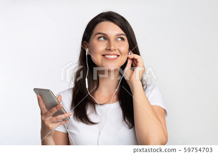 Woman In Earphones Listening Music On Smartphone Standing, Studio Shot 59754703