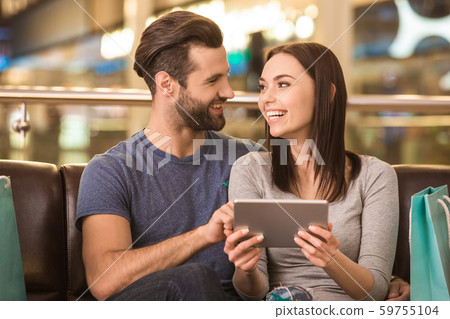 Young adult husband and wife using tablet computer in shopping mall Young adult husband and wife using tablet computer in shopping mall 59755104