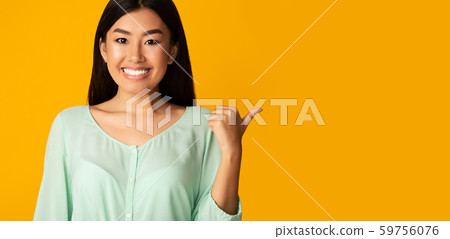 Smiling asian girl pointing aside at copy space Smiling asian girl pointing aside at copy space 59756076
