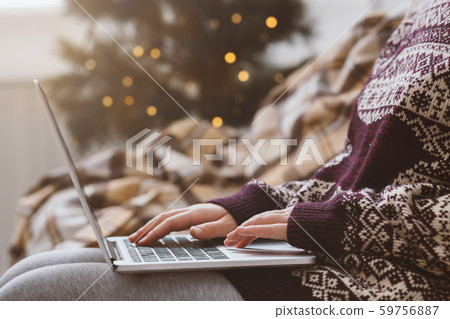 Woman in warm sweater using laptop over Christmas decorating room 59756887