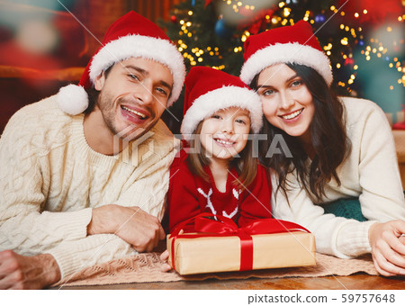 Portrait of smiling family laying on floor by xmas tree 59757648