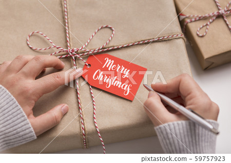 Woman signing Christmas and new Year gifts on white table 59757923